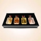Top-down view of four Swiss Miss mini perfume bottles neatly set inside a black velvet gift box insert.