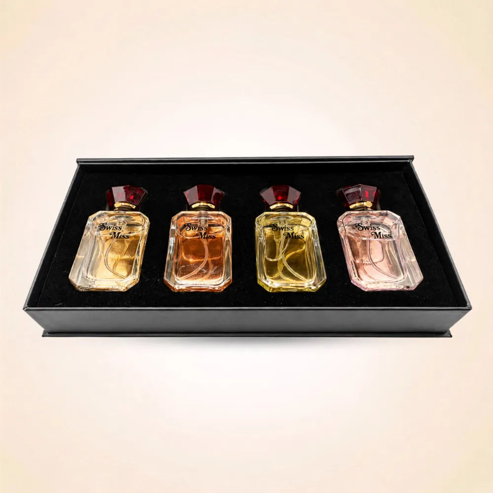 Top-down view of four Swiss Miss mini perfume bottles neatly set inside a black velvet gift box insert.