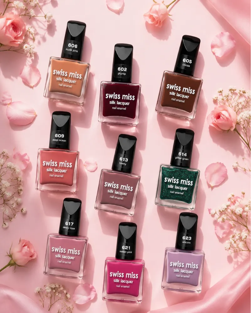 Flat lay display of Swiss Miss Silk Lacquer nail polish bottles in various shades surrounded by pink rose petals and flowers.