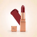 Swiss Miss Silk Lipstick in shade Cherry Brown (709) in gold bullet packaging shown alongside a textured cream color swatch.