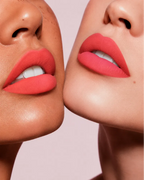 Close-up shot of two models with different skin tones wearing Swiss Miss Silk Lipstick in shade Coral Ice (727).
