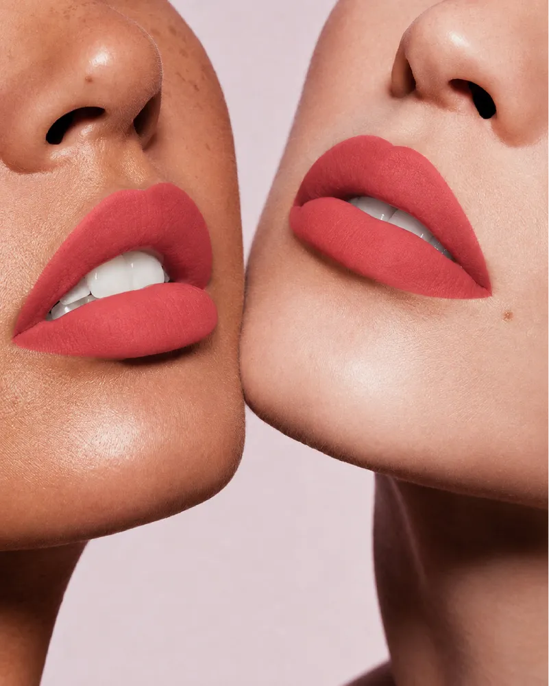 Close-up shot of two models with different skin tones wearing Swiss Miss Silk Lipstick in shade Coral Pink (726).