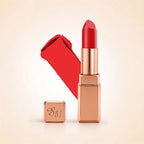 Swiss Miss Silk Lipstick in shade Coral Pink (726) in gold bullet packaging shown alongside a textured cream color swatch.