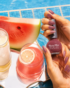 Woman holding Swiss Miss Get Set Go quick dry nail polish in Sugar Pink 209 with matching mauve pink manicure by a pool.